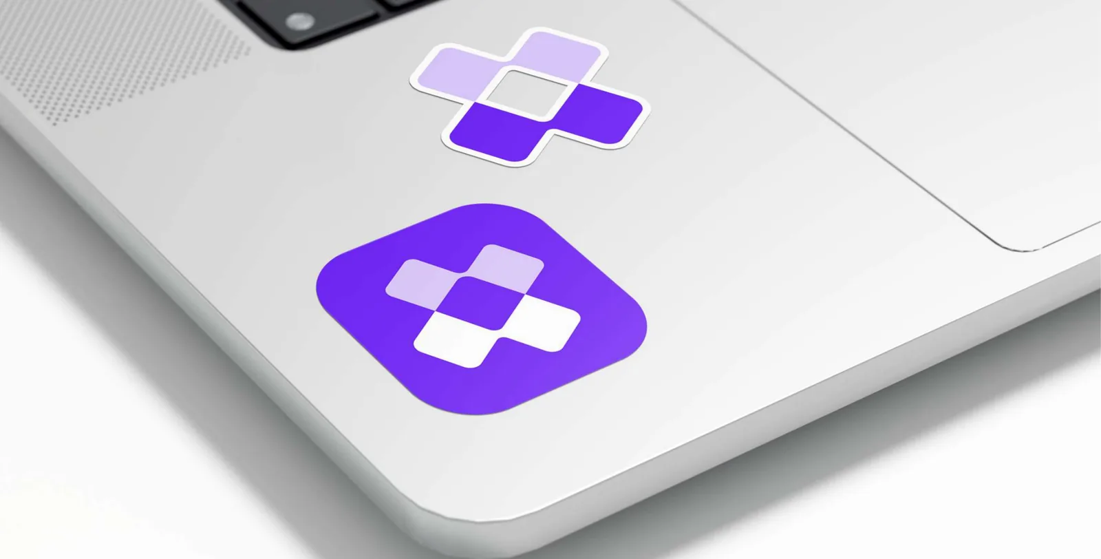 Two Lodol symbol stickers on a laptop, one die-cut and one on an Electric Indigo rounded square.